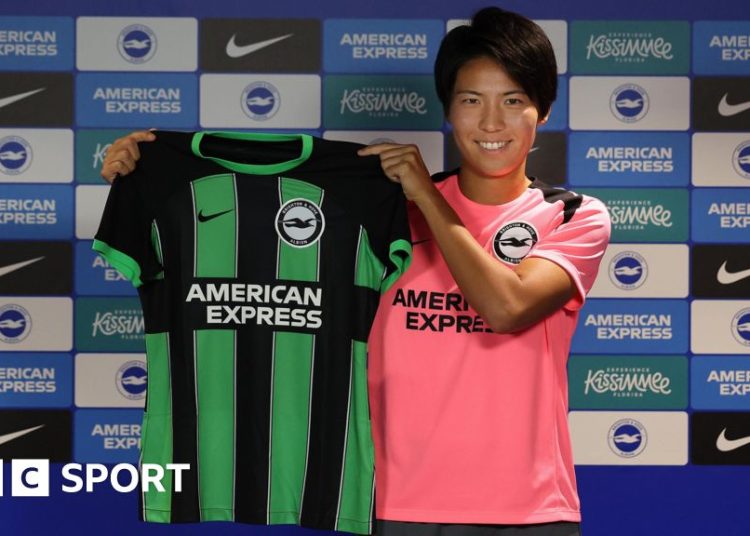 Japan striker Kiko Seike holds up a Brighton shirt at her unveiling